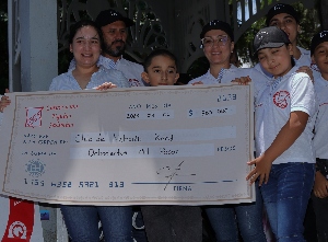 Niños del Club de Natación Koral sostienen cheque simbólico por $800 mil.