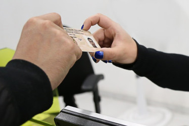 Mano masculina y otra femenina sostienen una licencia de conducción.