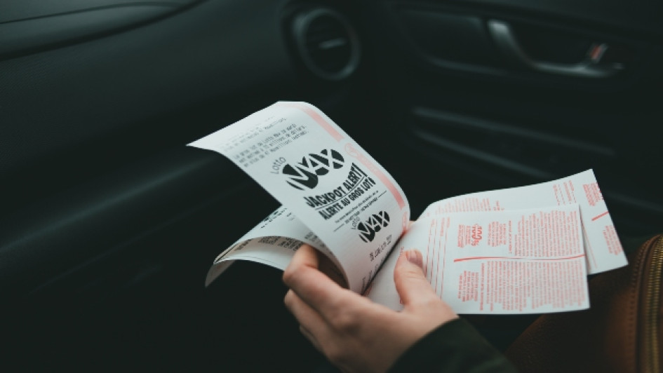 Lotería de Manizales resultado noviembre 23 de 2022 Mujer en un carro con billetes de lotería en la mano.