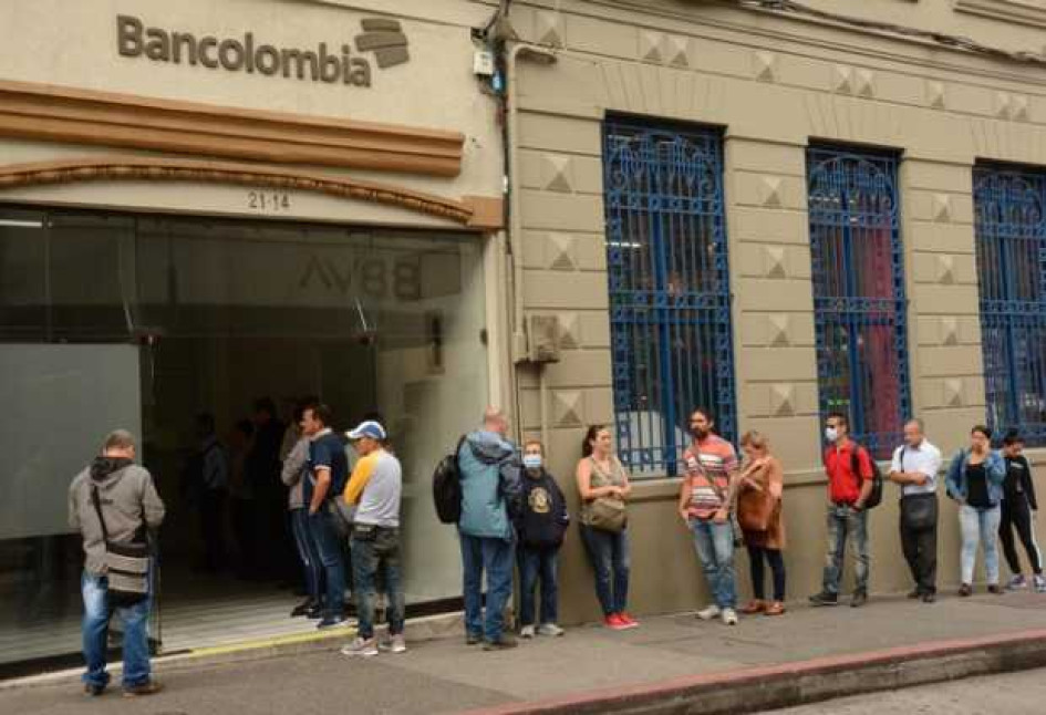 Gente hace fila afuera de una oficina de Bancolombia en el centro de Manizales.
