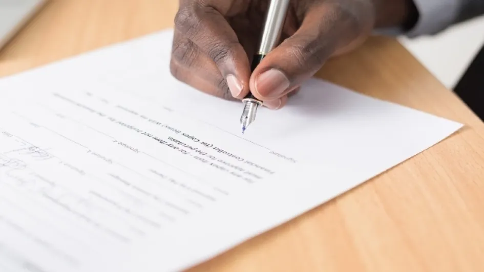 Que-es-un-derecho-de-peticion Hombre firma un documento impreso sobre una mesa.