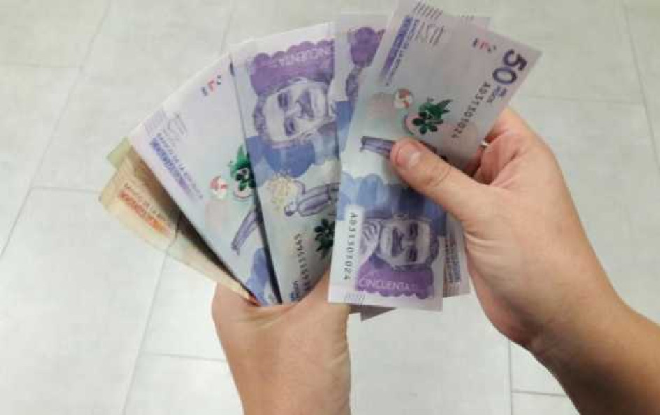 Carreras-mejor-pagadas-de-Colombia Mano con billetes de pesos colombianos.