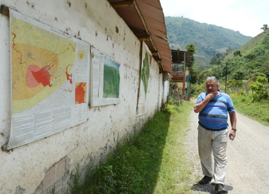 Jorge Enrique Jaramillo Toro, coordinador de la brigada de primeros respondientes de la vereda Viejo Rioclaro, camina por la única vía de la vereda y a su lado izquierdo se evidencian los mapas informativos. Jorge Enrique Jaramillo Toro, vereda Viejo Rioclaro