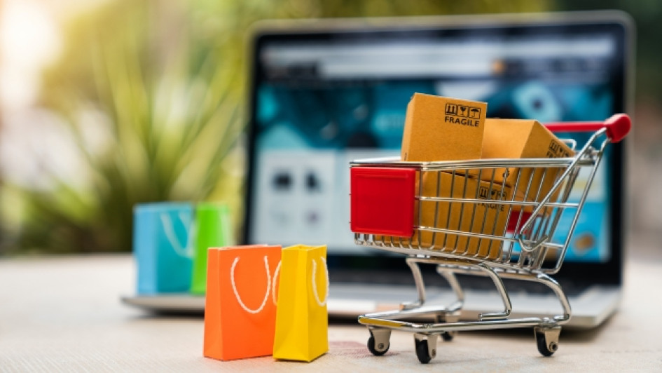 Mejores-ofertas-Amazon-Prime-Day Carrito de supermercado con bolsas y cajas de compras con un computador portatil detrás.