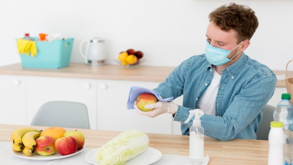 Qué-desinfectantes-pueden-ser-usados-directamente-en-los-alimentos Hombre usando tapabocas desinfecta frutas con un pañuelo.