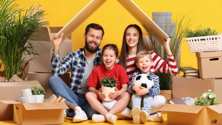 Cómo-saber-a-qué-caja-de-compensación-estoy-afiliado Familia feliz sentada bajo un cartón al lado de muchas cajas.