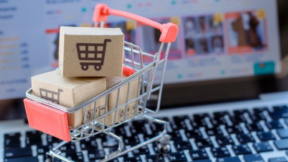Como-comprar-en-amazon-desde-colombia Carro de compras con cajas de cartón encima de un teclado de computador.