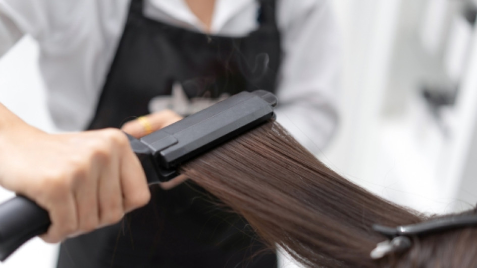 Se-puede-planchar-el-cabello-despues-de-la-keratina Estilista le plancha el cabello a una mujer.