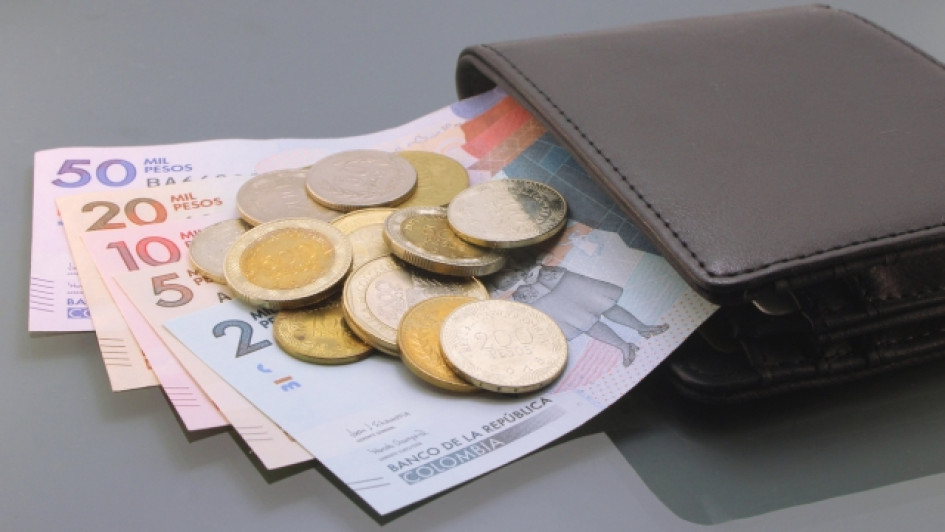 cuanto-vale-un-dia-y-una-hora-de-trabajo-en-Colombia Billetera con billetes y monedas colombianas saliéndole.