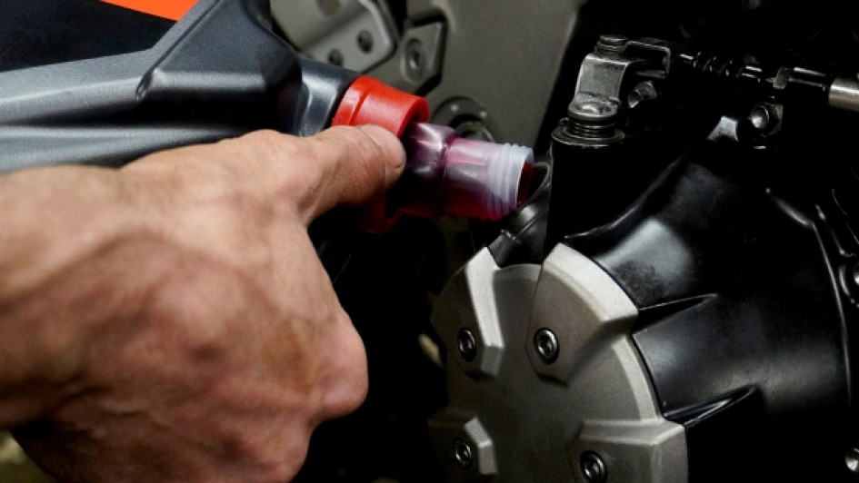 Mano echando aceite al motor de una moto.