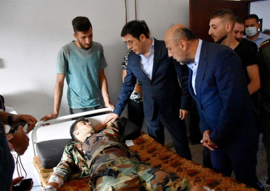 Siria La foto proporcionada por la agencia oficial de noticias árabe siria (SANA) muestra al Ministro de Salud sirio, Hassan al-Ghabash (C), visitando a un herido después de un ataque con aviones no tripulados que tuvo como objetivo una ceremonia de graduación de la academia militar Homs, Siria.