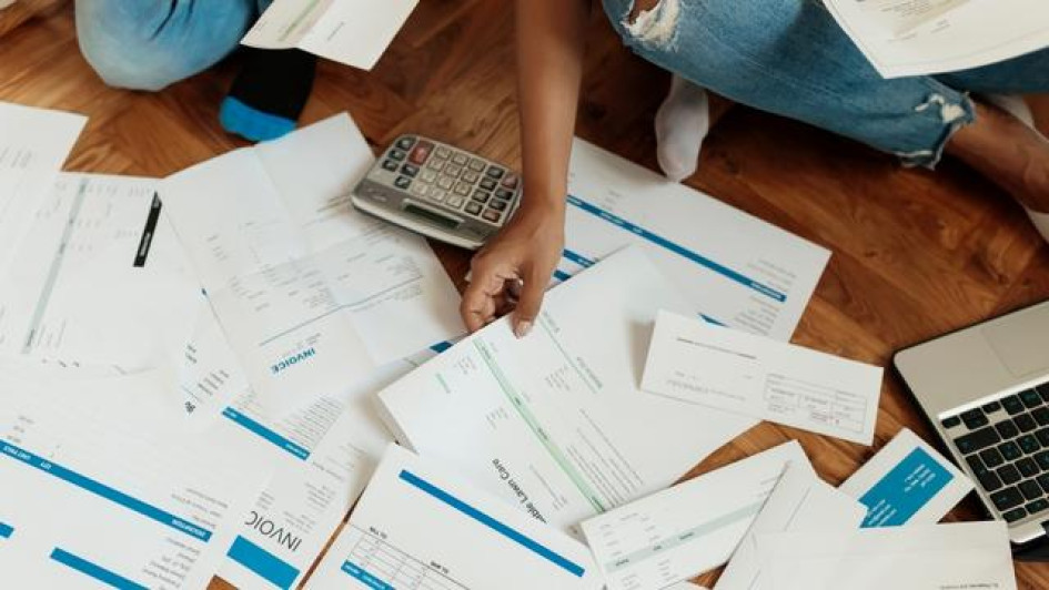Cuando-prescribe-una-deuda-en-Colombia Persona sentada en el piso con facuras y una calculadora.