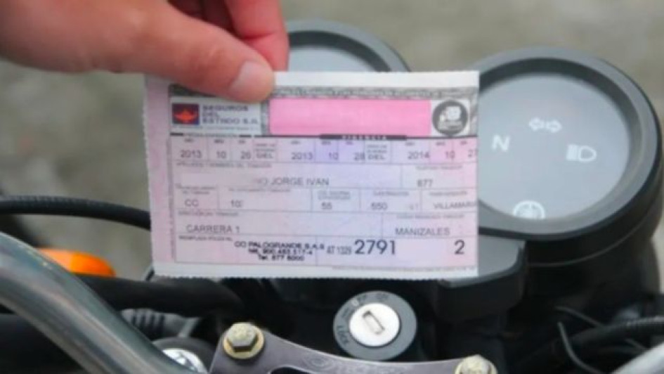 Precio-del-SOAT-para-moto-Cuánto-vale-el-SOAT-para-moto Mano sosteniendo un SOAT frente a una moto.