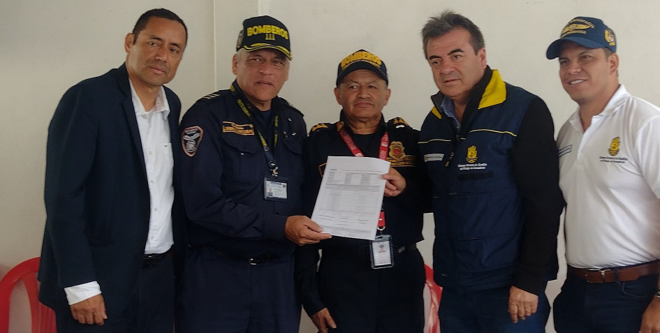 Olmedo López, director de la UNGRD (chaleco azul), entrega el acta en la que consta los equipos que recibirá Bomberos Voluntarios de Villamaría. entrega