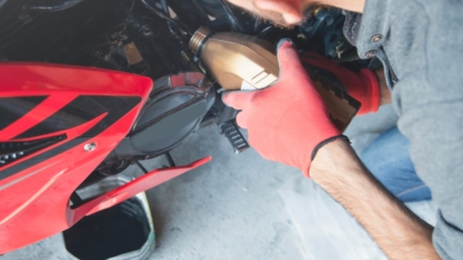 Para-que-sirve-el-aditivo-en-la-gasolina Hombre le echa aceite al motor de una moto