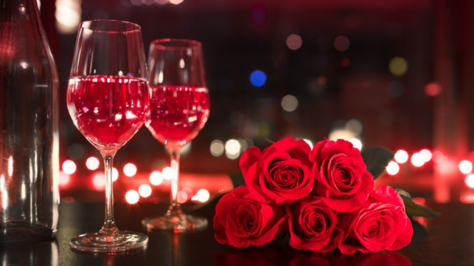 Cuando-es-san-valentin-en-colombia Copas con vino rosado al lado de rosas rojas.