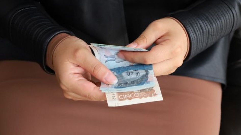 Como-pagar-facturas-de-servicios-publicos-desde-Susuerte Persona con billetes de pesos colombianos.