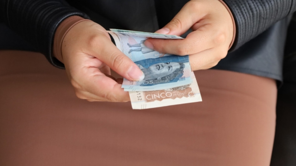 Como-acceder-al-subsidio-de-desempleo Mano sosteniendo billetes de Colombia